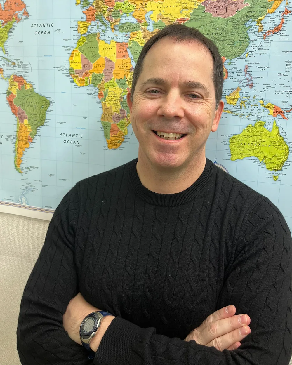 James, founder and teacher at BumbleB English, in front of a world map